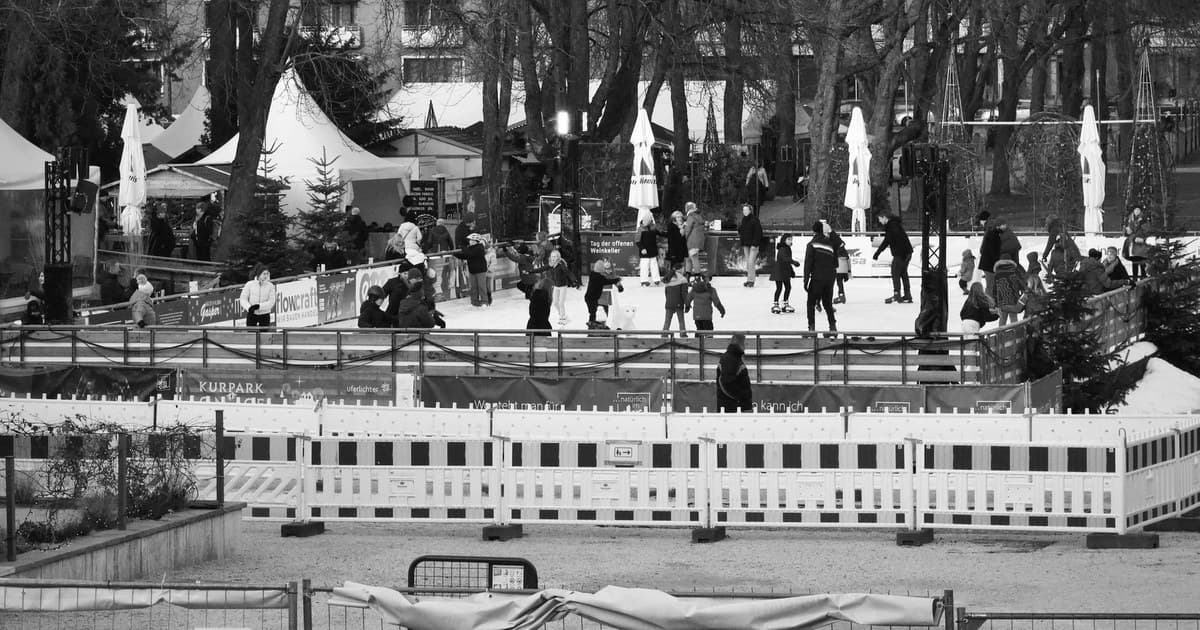 People enjoying ice skating at an outdoor rink surrounded by winter scenery.